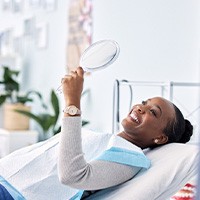 Woman smiling at reflection in handheld mirror