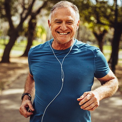 Senior man smiling while jogging outside
