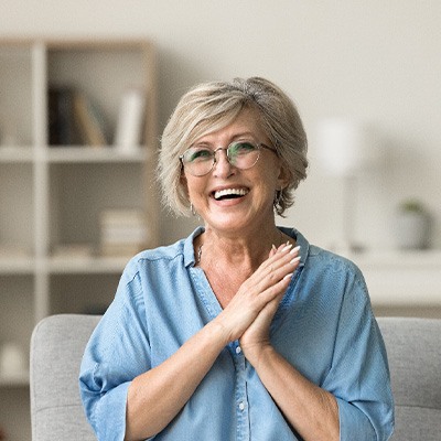 Senior woman with glasses smiling on couch at home