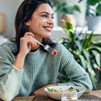 Woman smiling while eating healthy meal at home