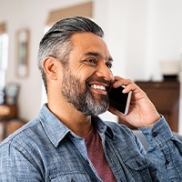 Man smiling while talking on phone at home