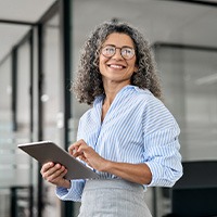 Woman smiling while holding tablet in office