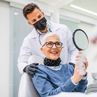 Woman smiling at reflection in handheld mirror