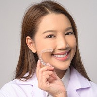 Smiling patient holding clear aligner