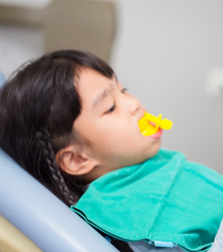 Young girl in dental chair with fluoride trays on her teeth