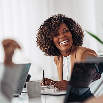 Woman smiling while taking notes during meeting