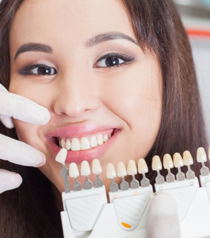 Young woman smiling while getting veneers from her cosmetic dentist