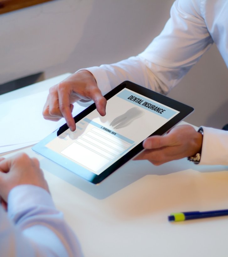 Two people looking at dental insurance forms on tablet