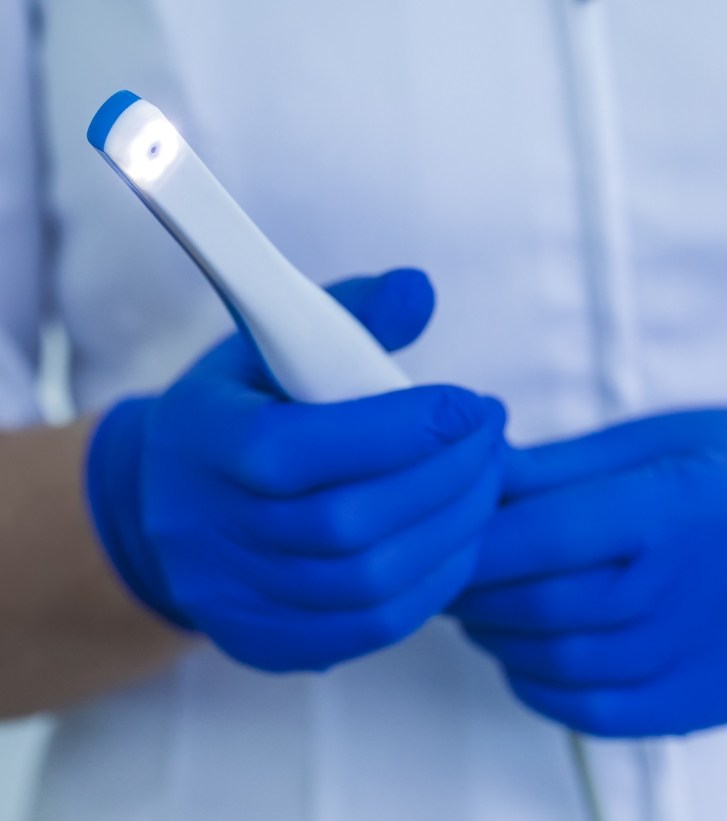 Dental professional holding a thin white intraoral camera