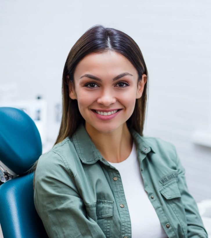 Woman in green shirt smiling in dental chair
