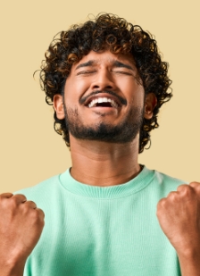 Man in light green shirt smiling with eyes closed and hands in victory pose