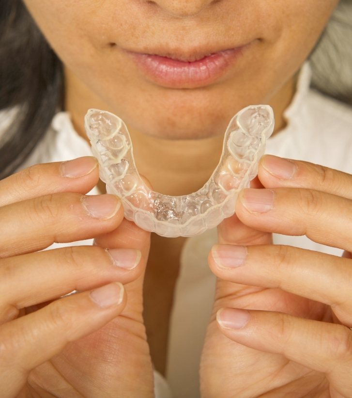 Person holding an Invisalign aligner close to their mouth