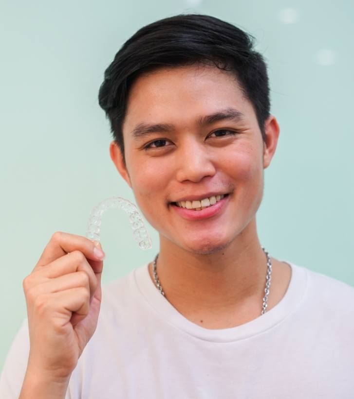 Smiling young man holding an Invisalign tray
