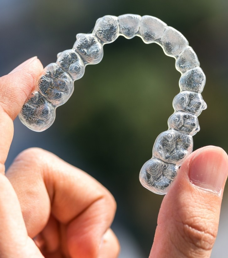 Hand holding an Invisalign aligner