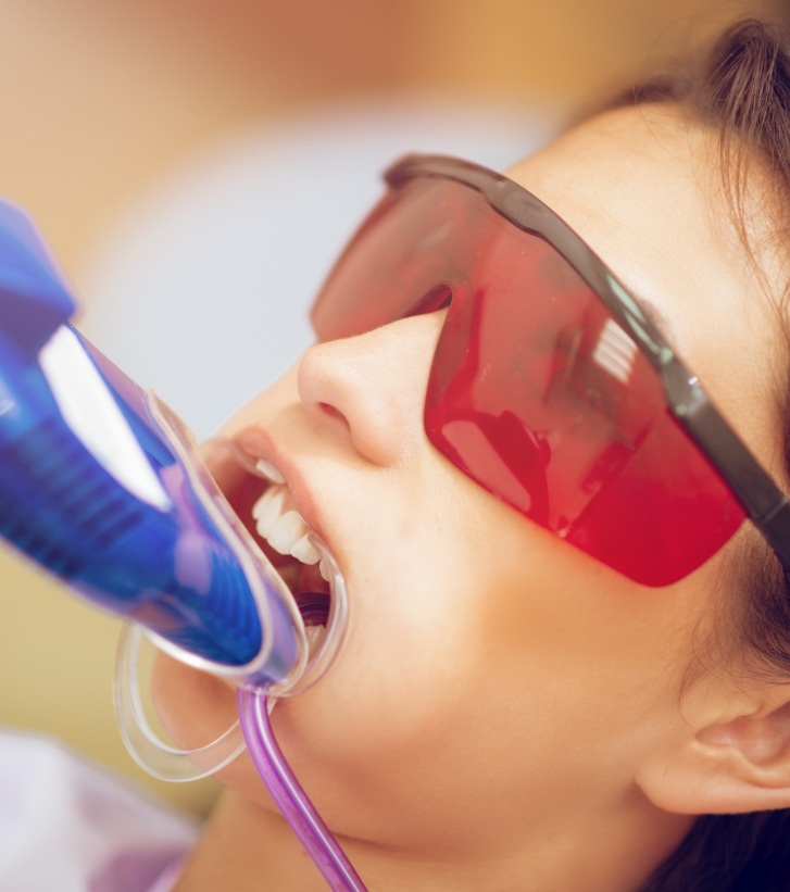 Young woman in dental chair with fluoride trays on her teeth