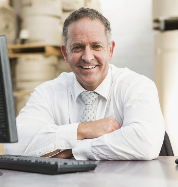 Man smiling at desk after replacing missing teeth in Beaverton