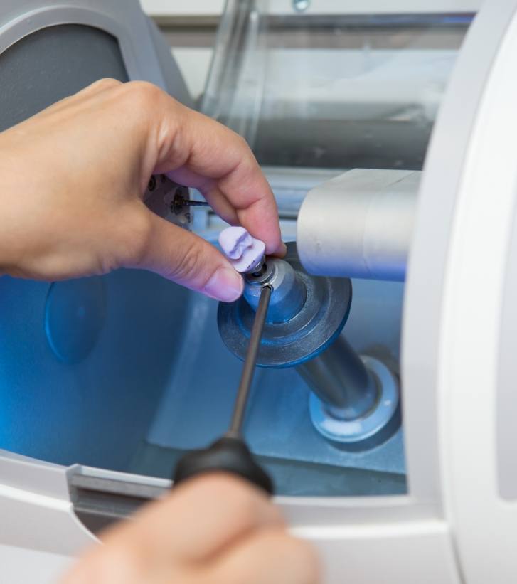 Dentist holding a CEREC one visit dental crown in a milling machine