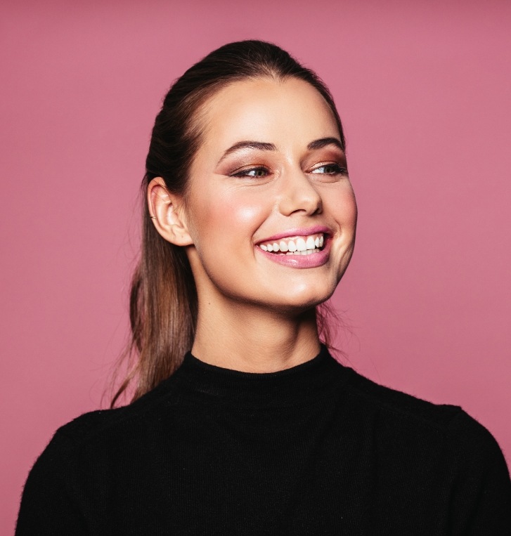 Woman smiling against pink background