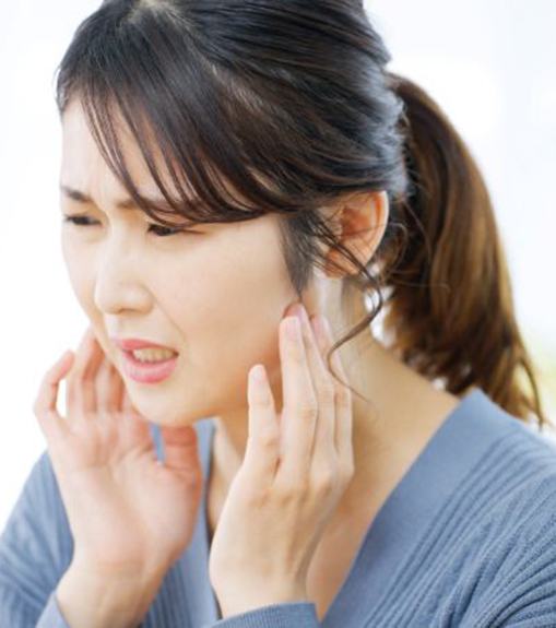 Woman frowning as she experiences symptoms of TMJ disorder