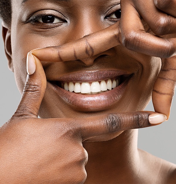 Woman framing her bright smile with 4 fingers