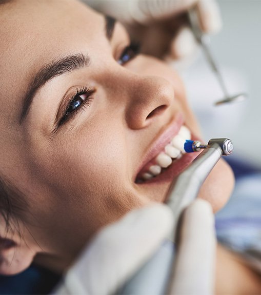 Woman in dental chair smiling during teeth polishing