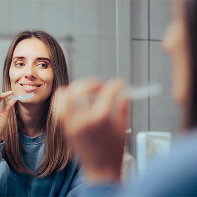 Woman smiling at reflection about to insert teeth whitening tray