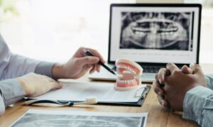 Dental consultation with X-ray in background and model of mouth in foreground.